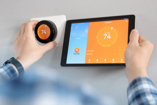 istock Man is Adjusting a  temperature using a tablet with smart home app in modern living room 1571186845