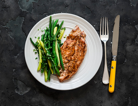 Turkey fillet chop and green string beans - a delicious diet lunch on a dark background, top view