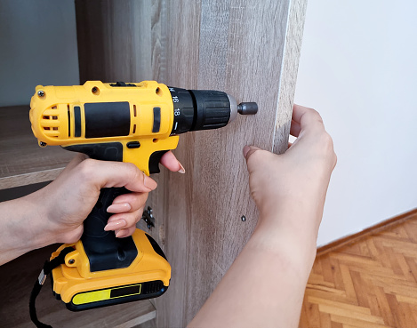 The carpenter screws the screw into the boards with a screwdriver