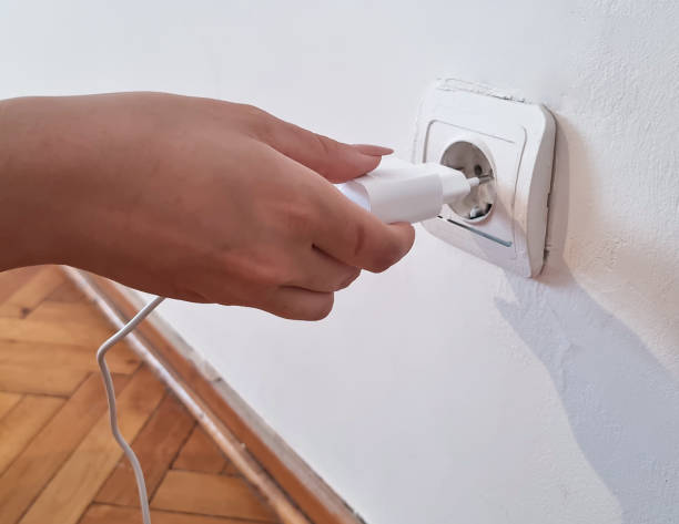 istock Hand turns on, turns off charger in electrical outlet 1571246379