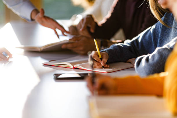 istock Close up of unrecognizable college student writing in a notebook. 1571255174