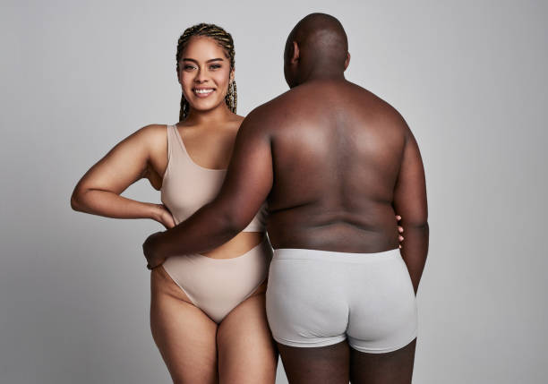 Hug, plus size and portrait of couple in studio in underwear for wellness, health and skincare. Natural, beauty and back of man and woman embrace on gray background for body positivity, care or love Hug, plus size and portrait of couple in studio in underwear for wellness, health and skincare. Natural, beauty and back of man and woman embrace on gray background for body positivity, care or love body positive couple stock pictures, royalty-free photos & images