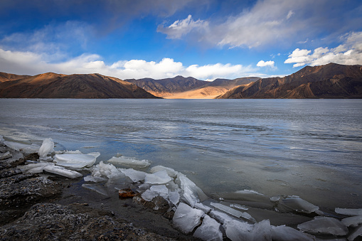 Icy formations, waves that appeared to be frozen in time on Pangong Lake's Shoreline, and mountains visible in the distance