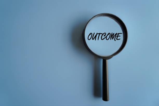 istock Top view image of magnifying glass on blue background with text OUTCOME. 1571284443