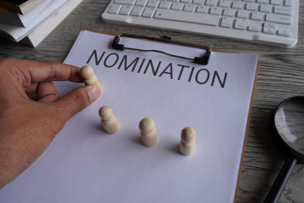 istock Hand pick wooden doll and text NOMINATION. 1571285995