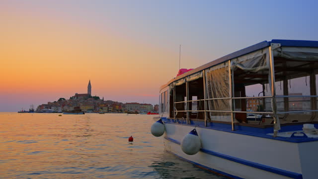 SLO MO Passenger Boat Floating on Calm Sea, with the Picturesque Old Town of Rovinj at Sunset