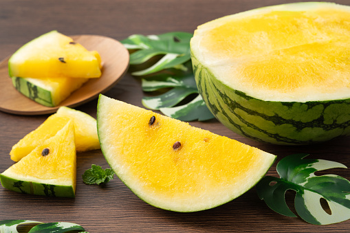 Sliced yellow golden watermelon in a plate on wooden table background ready for eating.