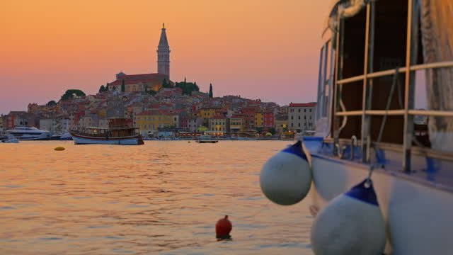 SLO MO Tourboat Floating on Sea, with Charming Old Town of Rovinj at Sunset