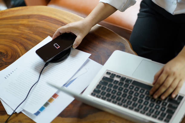 istock Charging mobile phone battery with wireless charging device in the table. Smartphone charging on a charging pad. Mobile phone near wireless charger Modern lifestyle technology concept 1571326681