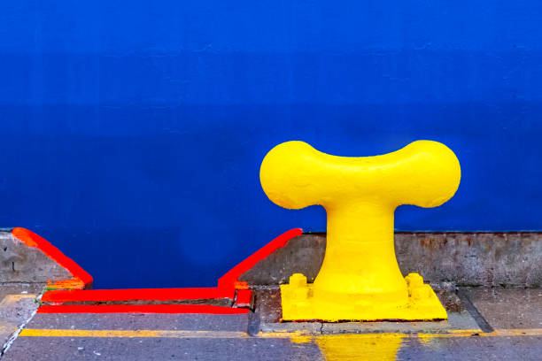 A bright yellow harbour bollard with blue background.