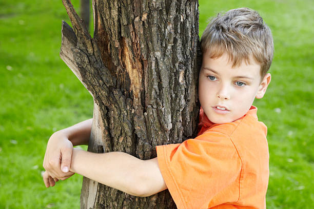 istock Portrait of boy, that stands hugging tree in park 157140390