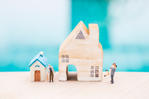 Miniature people with house model over blurred background, family house and retirement home, property business