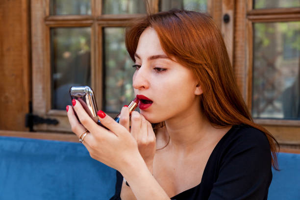 istock A girl in a cafe at a table paints her lips with red lipstick 1571421387