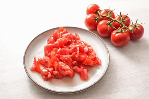 Tomatoes, whole and chopped on a plate, ingredient for various dishes, healthy cooking concept, copy space, selected focus, narrow depth of field