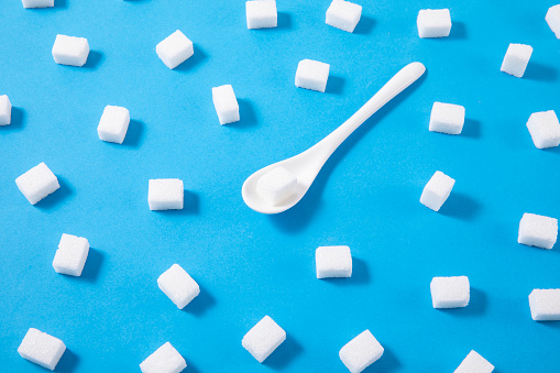 Choice between granulated sugar and sugar cubes in bowls on a white background. Top view