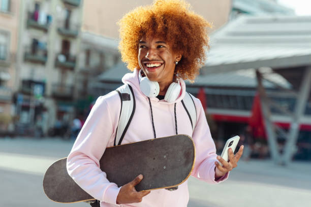 istock An African American man is holding a smart phone and skateboard 1571432379