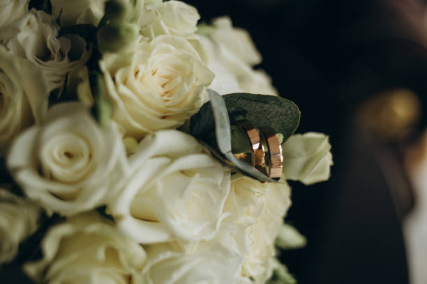 istock Wedding rings and roses bouquet 1571442236