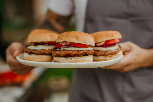istock A young man serving and eating a hamburger on a barbecue party outside 1571451972