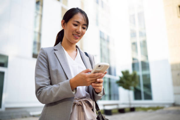 istock Businesswoman using phone in financial district 1571458866