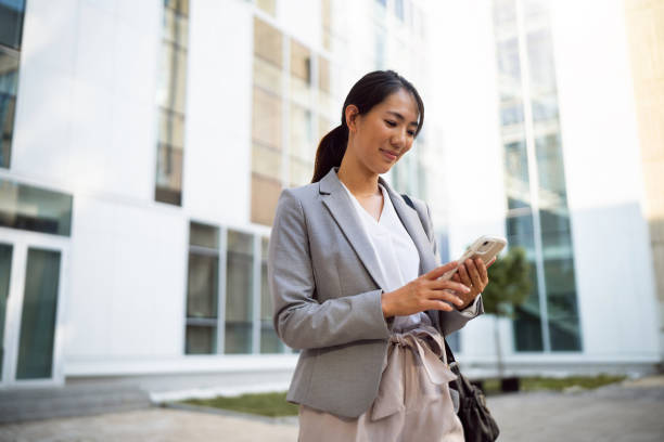 istock Businesswoman using phone in financial district 1571460143