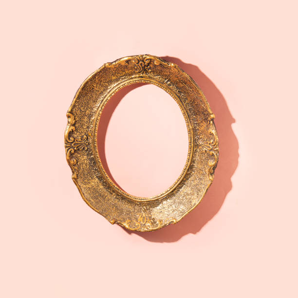 istock Oval vintage gilt frame, empty, on a pastel pink wall. 1571476236