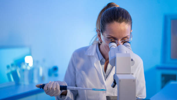 istock Female research scientist is analysing a sample on her microscope in a microbiology lab 1571480221