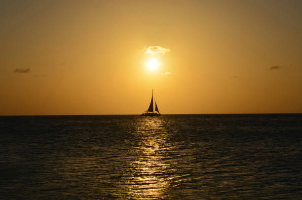 voilier en silhouette sur les eaux océaniques à aruba - sailing sailboat sunset aruba photos et images de collection