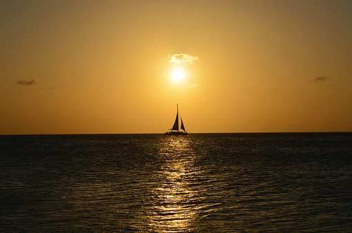 Beautiful sailboat silhouetted on the ocean waters under sail in Aruba.