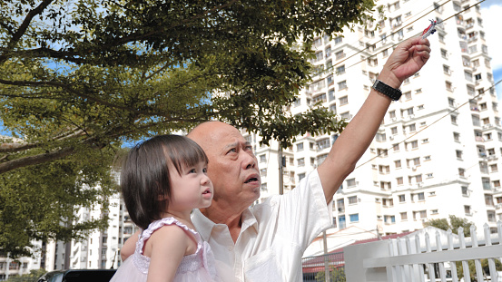 Asian grandfather playing airplane with granddaughter