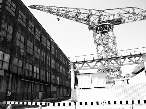 An old shore crane towers above an abandoned warehouse in La Ciotat, France. This is an interesting, high contrast image capturing the essence of heavy industry.
