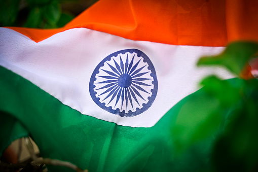 Stock photo showing a residential rooftop display of the National flag of India (tricolour) flying from wooden flagpole to celebrate Independence Day. Legally the flag can only be made of silk or khadi cloth.