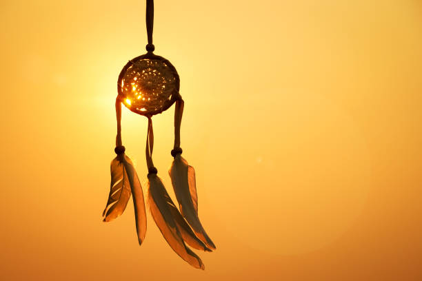 istock Dreamcatcher sunset , with white feather thread and beaded string. Handmade Dreamcatcher.The light of the setting sun. 1571511498