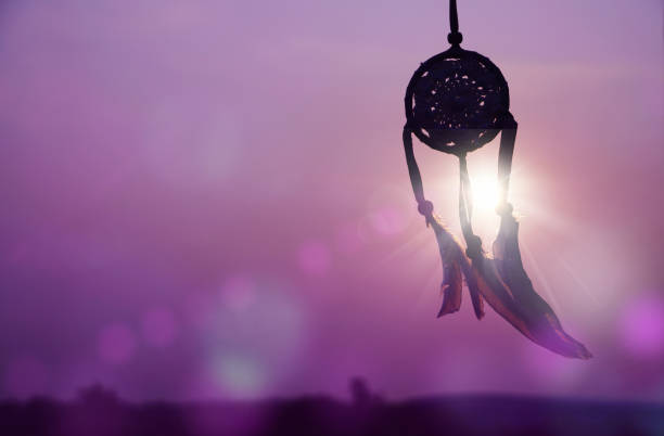 istock Dreamcatcher sunset , with white feather thread and beaded string. Handmade Dreamcatcher.The light of the setting sun. purple. 1571511500