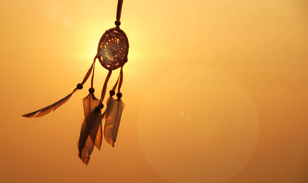 istock Dreamcatcher sunset , with white feather thread and beaded string. Handmade Dreamcatcher.The light of the setting sun. 1571511693