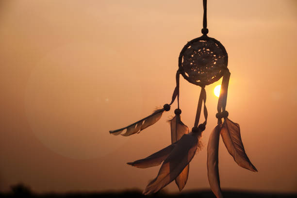 istock Dreamcatcher sunset , with white feather thread and beaded string. Handmade Dreamcatcher.The light of the setting sun. 1571512010