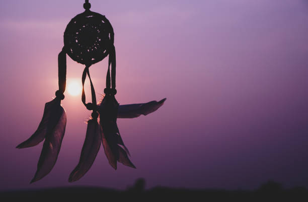 istock Dreamcatcher sunset , with white feather thread and beaded string. Handmade Dreamcatcher.The light of the setting sun. purple. 1571512011