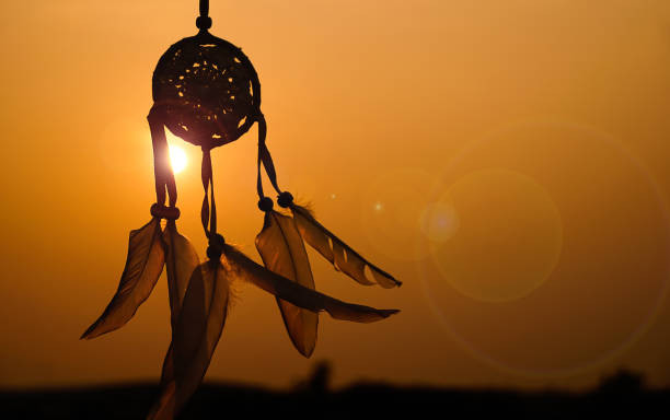 istock Dreamcatcher sunset , with white feather thread and beaded string. Handmade Dreamcatcher.The light of the setting sun. 1571512015