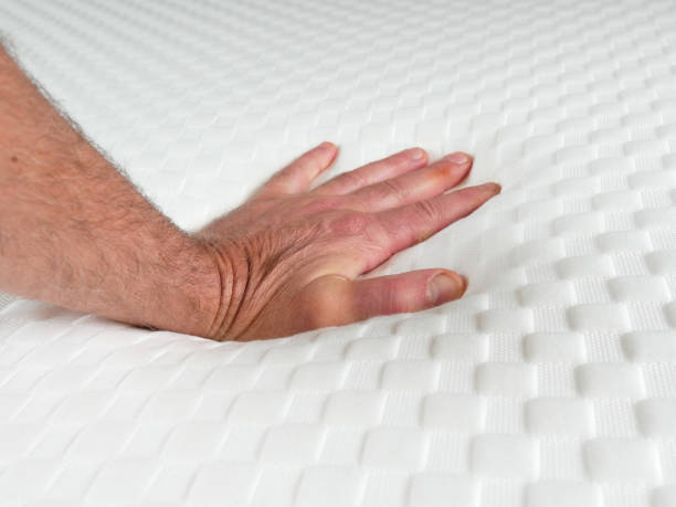 istock Man testing the softness of a new mattress. His hand sinks slightly 1571518942