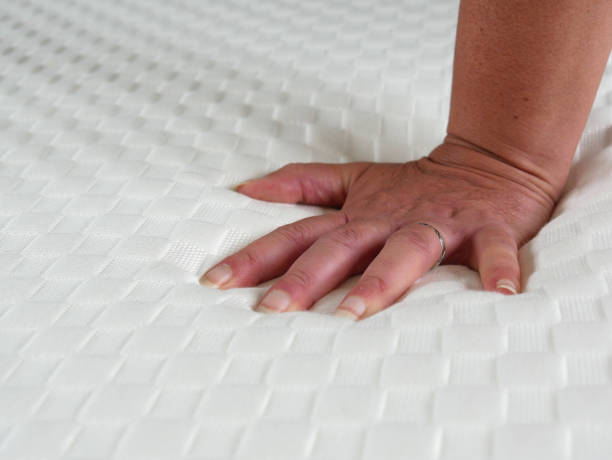 istock Woman testing the softness of a new mattress. Her hand sinks slightly 1571518968