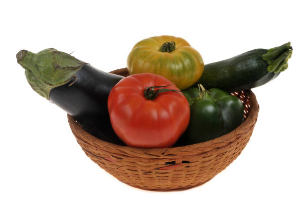 Wicker basket with assorted vegetables close-up on a white background