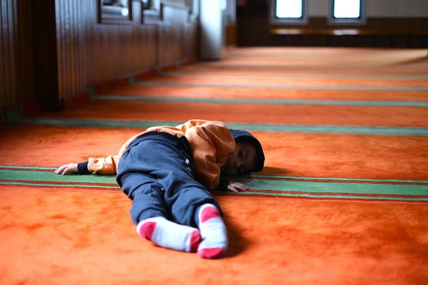 niño condenado al ostracismo por su familia se cubre la cara con las manos y se acuesta sobre alfombras - ostracized fotografías e imágenes de stock