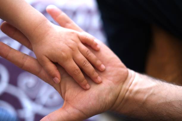 istock View of father and son's hands together 1571545327
