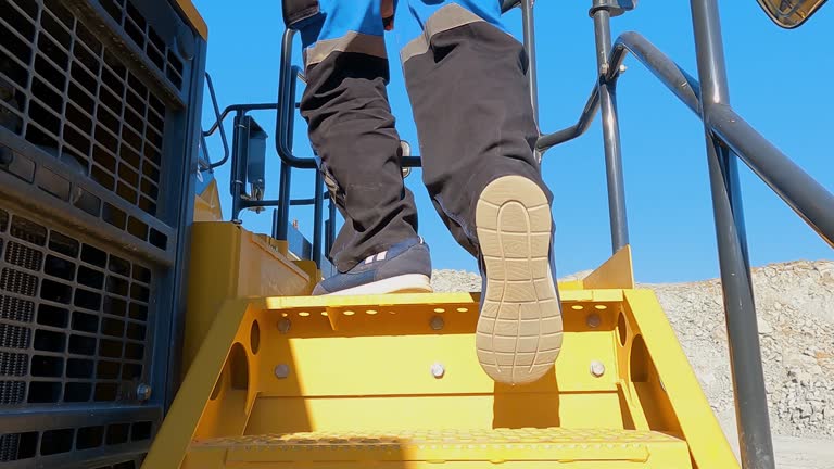 Driver climb on dumper truck stairs to start daily job of ore transportation ini open pit mine, slow motion