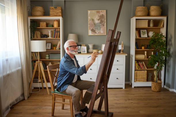 Elderly man painting on a canvas at home