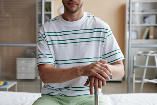 Close-up of patient sitting on couch with crutch during his visit to hospital