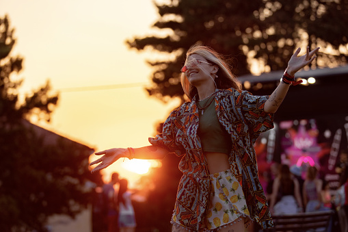 Carefree festival goer having fun while dancing at sunset.