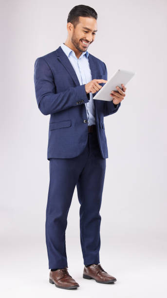 istock Happy asian man, business and tablet in studio for online planning, data trading and internet info on white background. Corporate trader, digital technology and network connection for app on website 1571581856