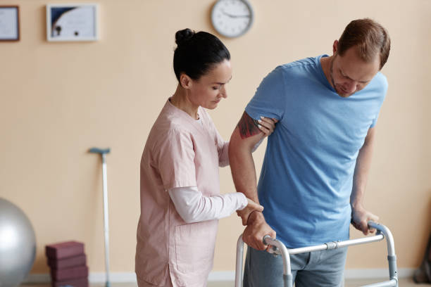 istock Doctor helping patient to walk 1571592550