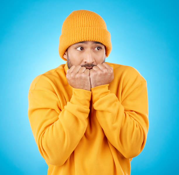 hombre nervioso, ansioso y asiático mordiéndose las uñas en el estudio con terror, miedo y asustado por la fobia secreta sobre fondo azul. estrés, suspenso y persona masculina esperando horror, alarma de peligro o malas noticias - nail biting guilt men anxiety fotografías e imágenes de stock