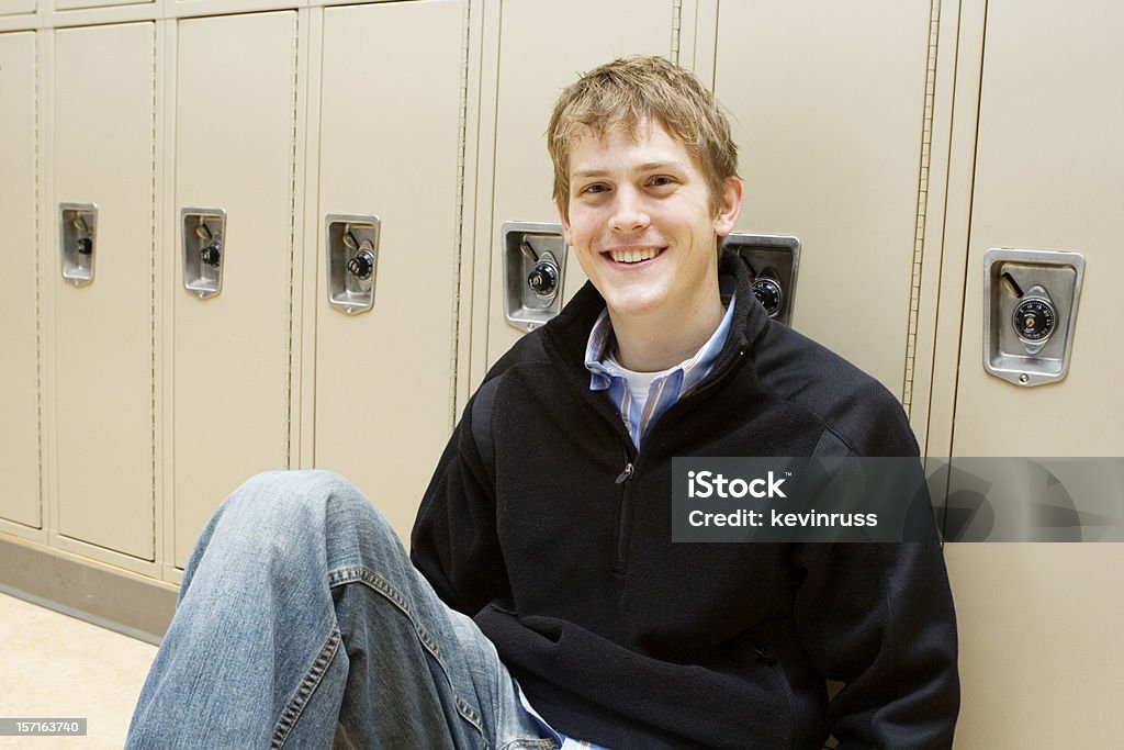 Caucasiano homem sentado na frente de algum armários - Foto de stock de Aluno do Ensino Médio royalty-free